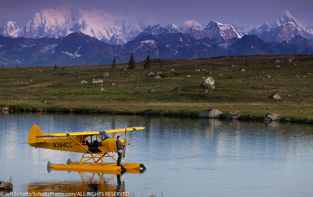 "A pilot fly fishes from his Super Cub floatplane on an unnamed lake in SouthCentral, Alaska with Alaska Range in the background, Summer"